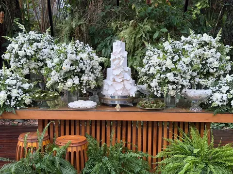 Mesa do bolo com arranjo floral em tons de verde e branco