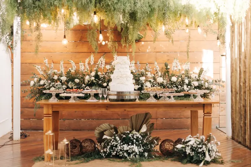 Recepção com mesa de madeira decorada com arranjos florais